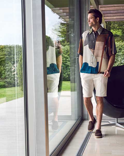 Modieuze zomerse outfit met een luchtige beige short en een opvallend printshirt, perfect gecombineerd voor een stijlvolle en ontspannen look.