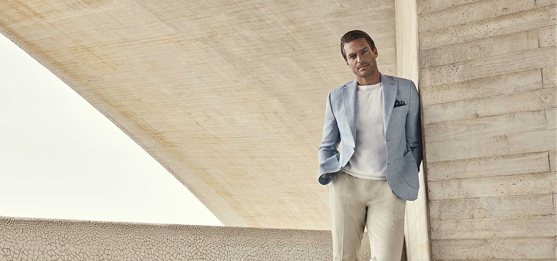 Carl Gross Colbert – Tijdloze Elegantie Carl Gross colbert in lichtblauw, gecombineerd met een wit T-shirt en beige broek voor een verfijnde zomerse uitstraling.