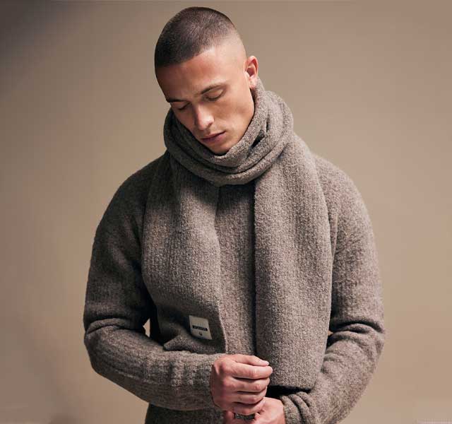 Genti Campagnebeeld – Beige Knit & Sjaal Genti beige knit met sjaal – modern campagnebeeld met zachte textuur – verkrijgbaar bij Van den Broek Herenmode Haarlem