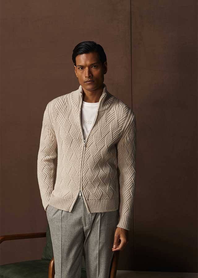 Man draagt de Gran Sasso Zip Knit 10155/19654-113 in beige bij Van den Broek Herenmode in Haarlem, staand tegen een warme achtergrond.