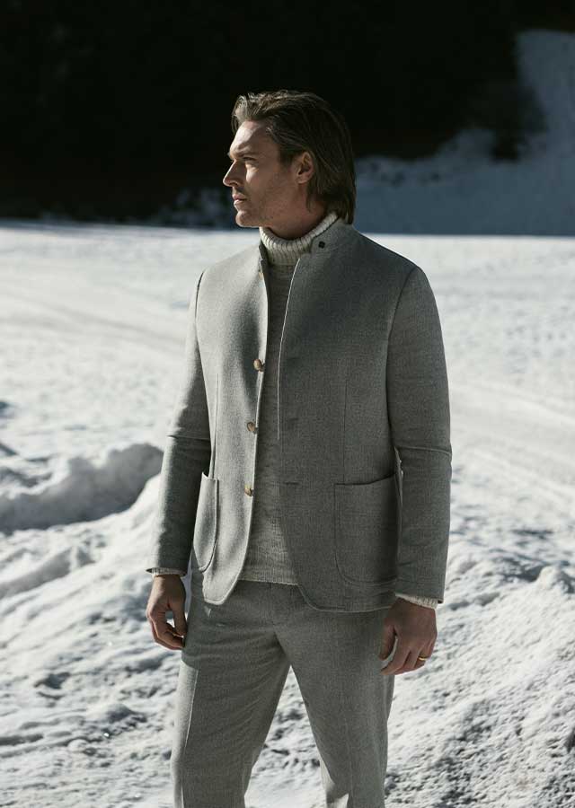 Gran Sasso Grijze Winterlook – Van den Broek Herenmode Haarlem Man in grijze Gran Sasso winterlook, gefotografeerd in de sneeuw, verkrijgbaar bij Van den Broek Herenmode in Haarlem.